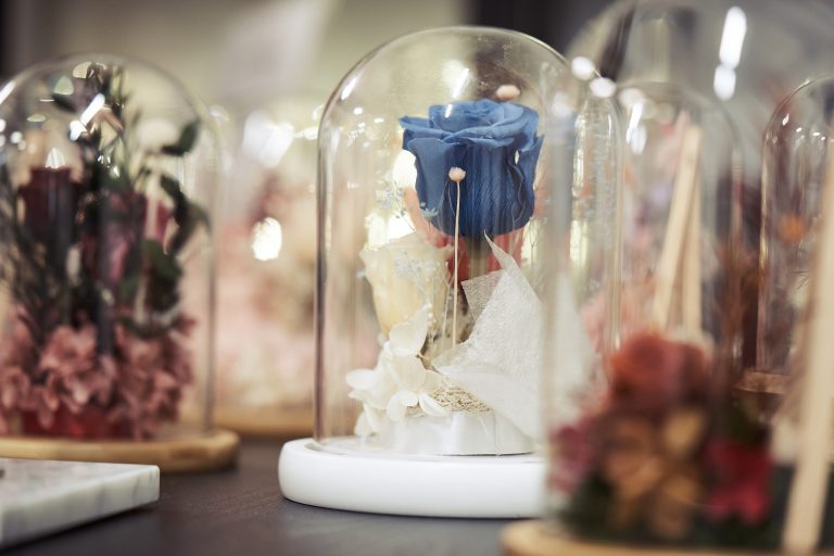 A blue preserved flower in a glass dome