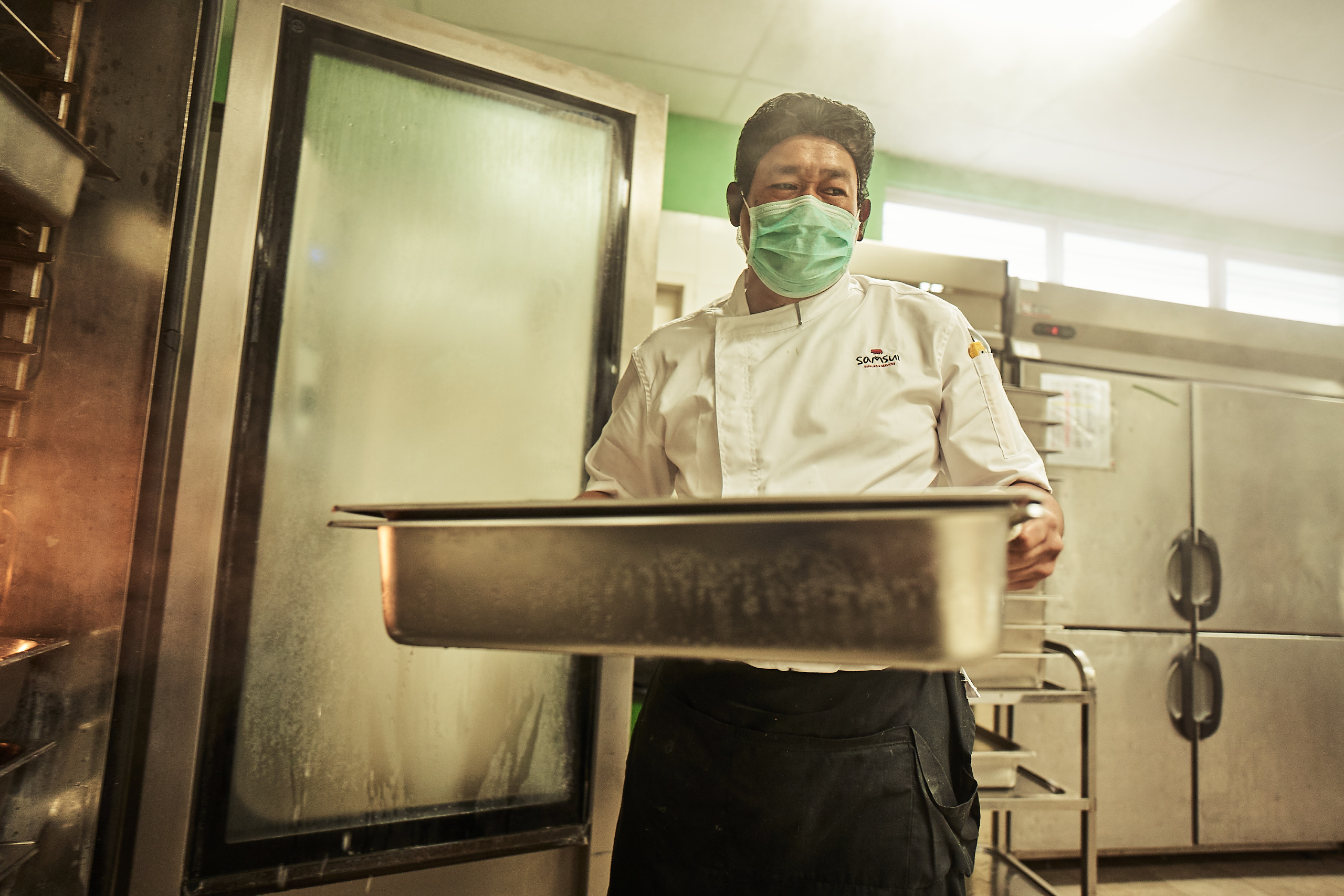 A chef is taking food out from an oven