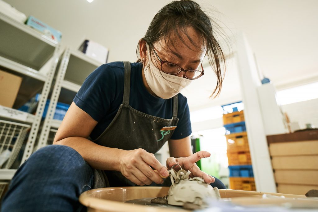 A woman in front of a pottery wheel