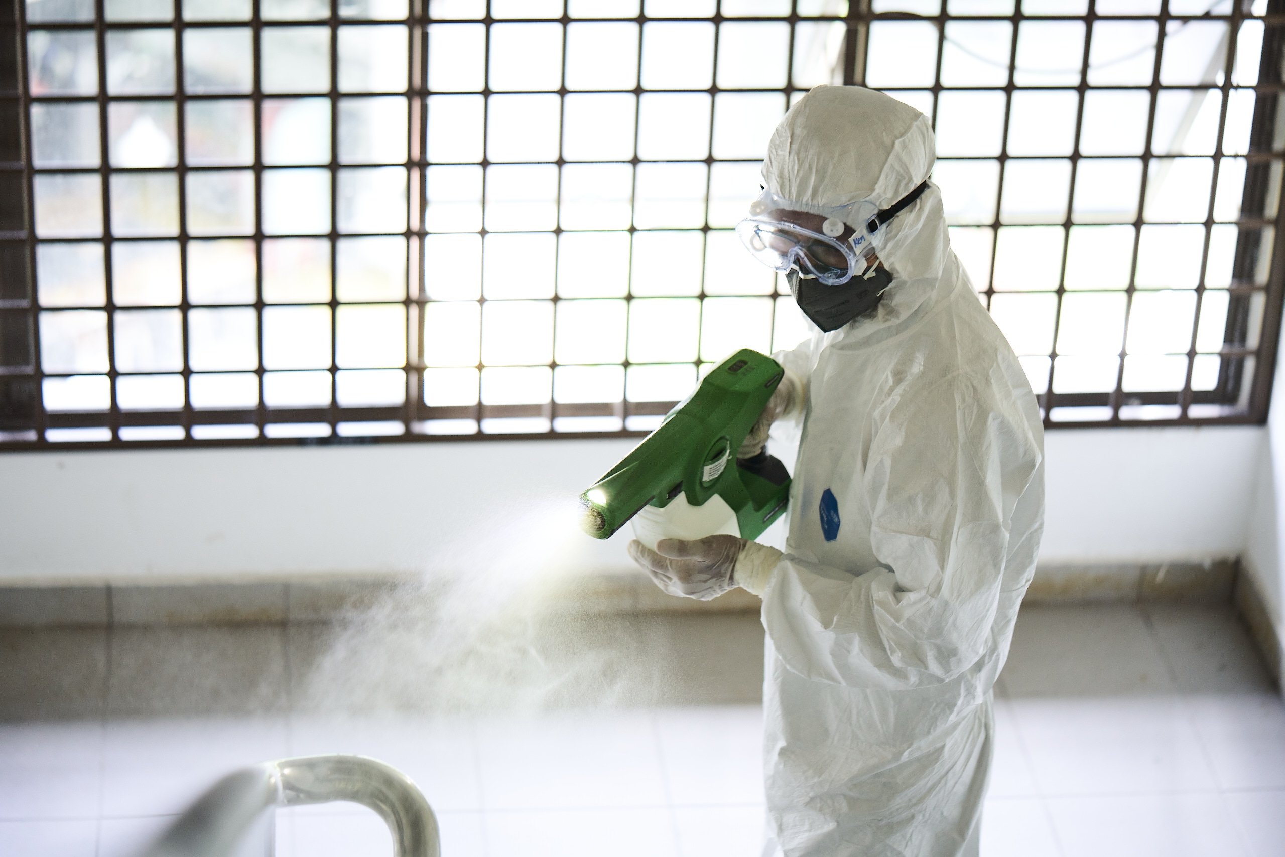 A man in PPE disinfecting a stairwell